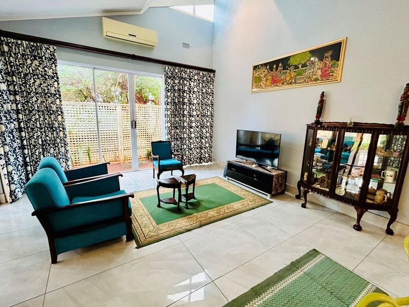 Spacious living room featuring high vaulted ceilings, large sliding glass doors providing natural light, and tiled flooring throughout.