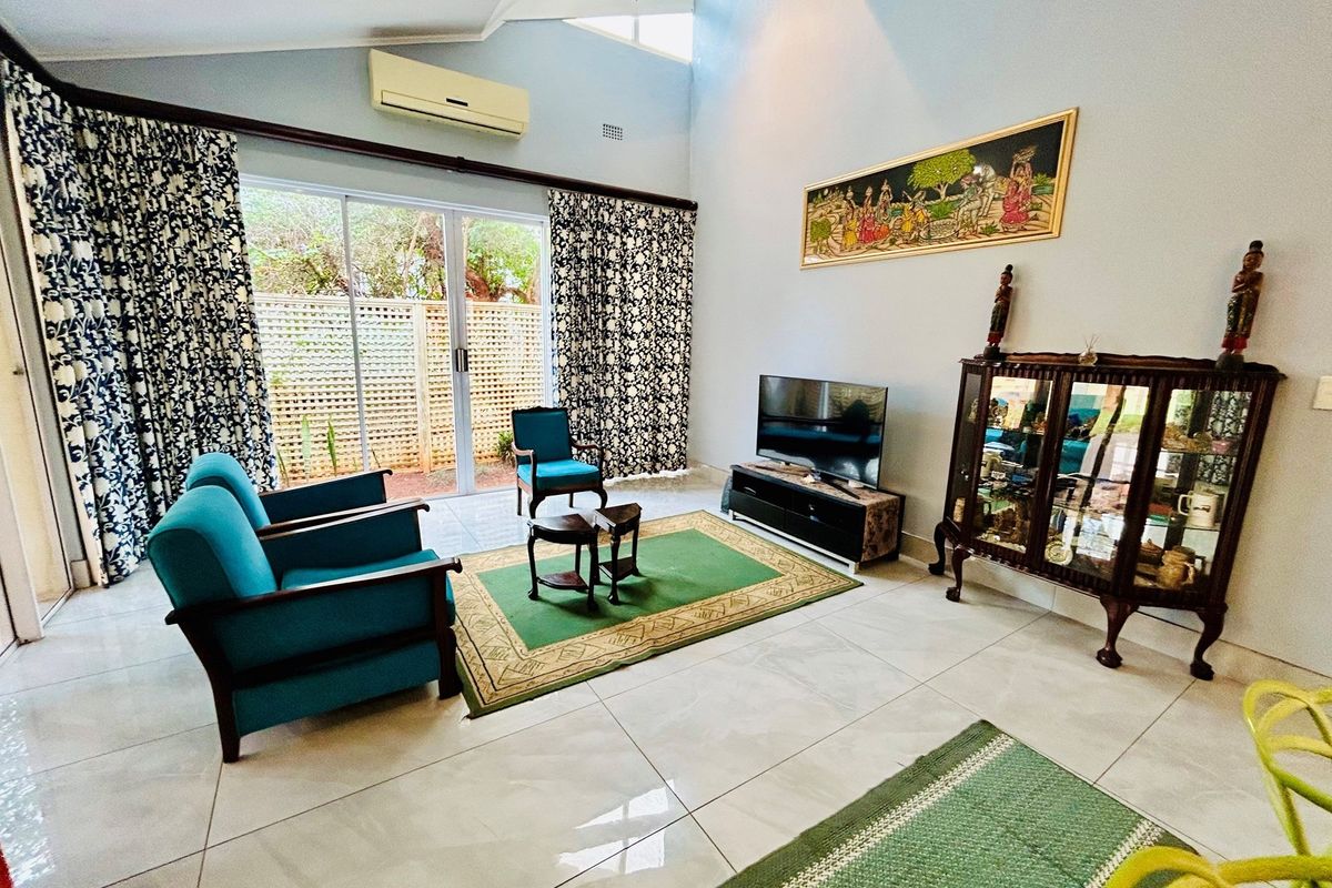 Spacious living room featuring high vaulted ceilings, large sliding glass doors providing natural light, and tiled flooring throughout.