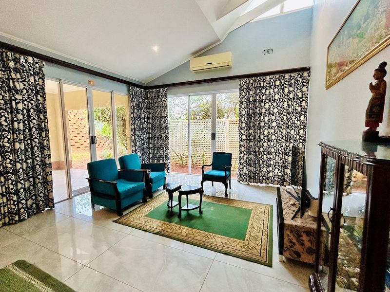 Spacious living room with high vaulted ceilings, tiled flooring, and large sliding glass doors providing direct access to the outdoor patio area.