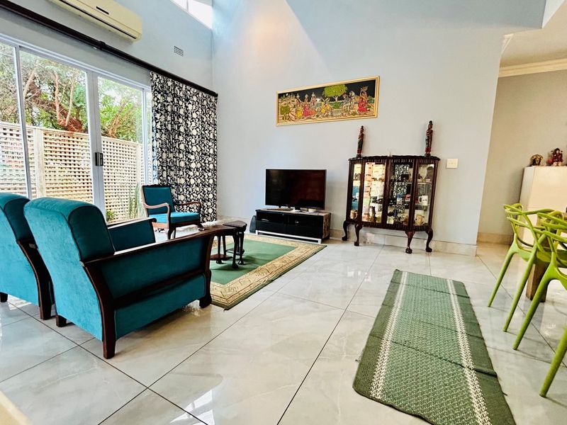 Spacious open-plan living and dining area featuring high vaulted ceilings, large sliding glass doors, and polished floor tiles.