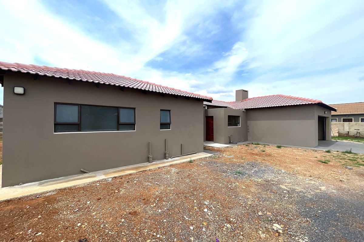 Rear view of the house featuring a tiled roof, painted exterior walls, and an unfinished garden area.