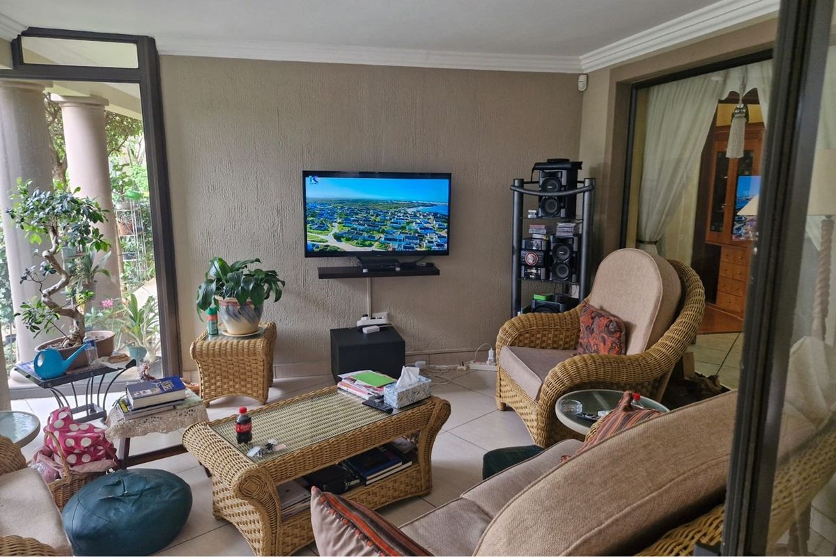 A comfortable living room featuring tiled flooring, coving, and large sliding glass doors that provide access to the outdoor area.