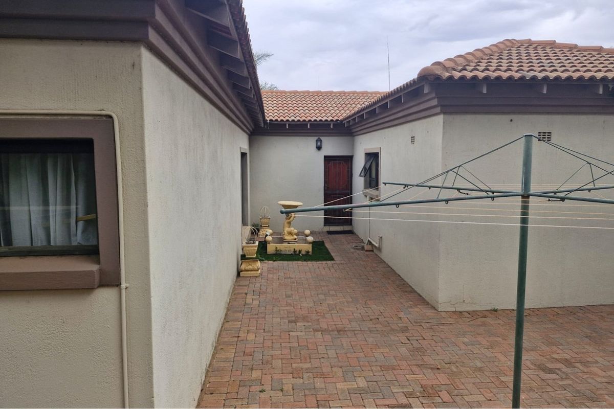 A paved rear courtyard area featuring terracotta roof tiles and stucco walls, providing a functional outdoor space between building wings.