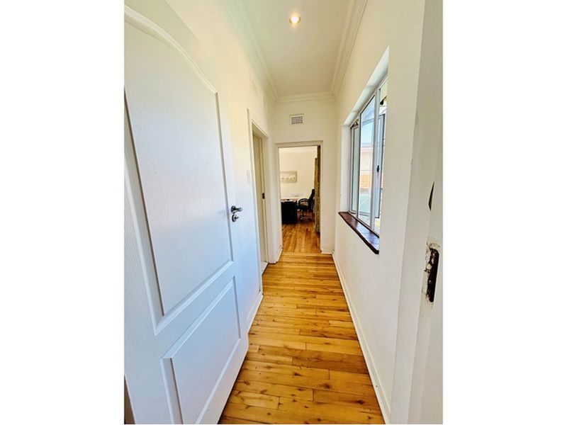 A bright hallway featuring polished timber flooring, crown molding, and access to adjacent rooms through classic panel doors.