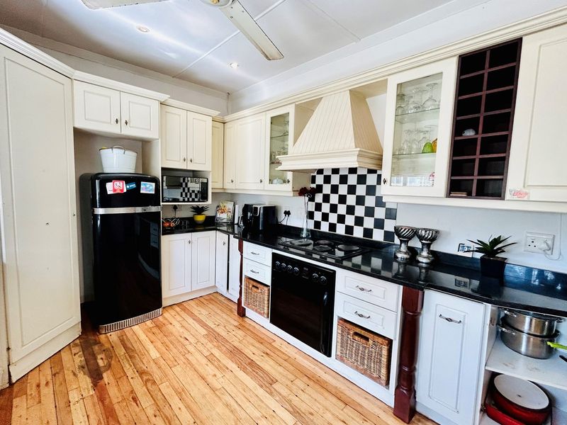 A classic kitchen featuring cream cabinetry, black granite countertops, a checkerboard tile backsplash, and integrated oven with extractor fan.