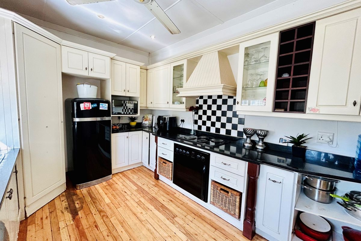 A classic kitchen featuring cream cabinetry, black granite countertops, a checkerboard tile backsplash, and integrated oven with extractor fan.