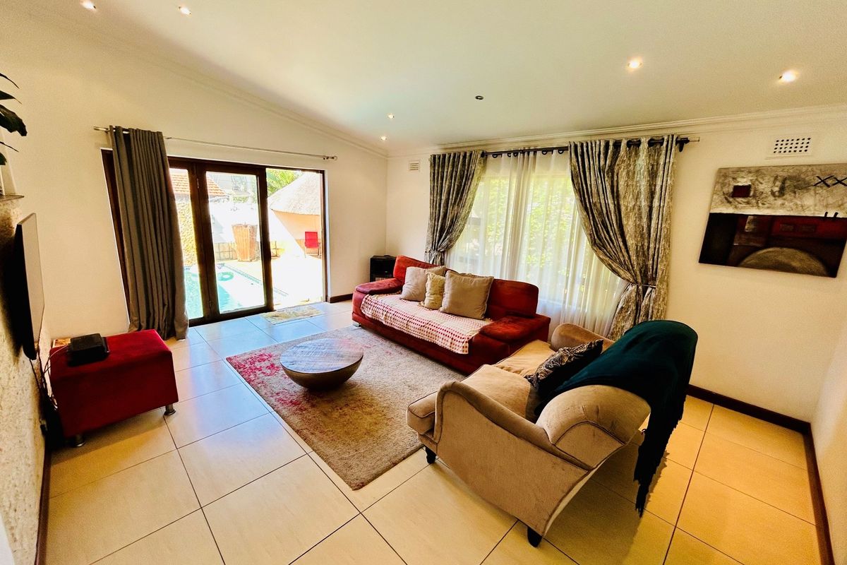 Spacious living room featuring large format floor tiles, recessed downlighting, and sliding glass doors providing direct access to the outdoor pool area.