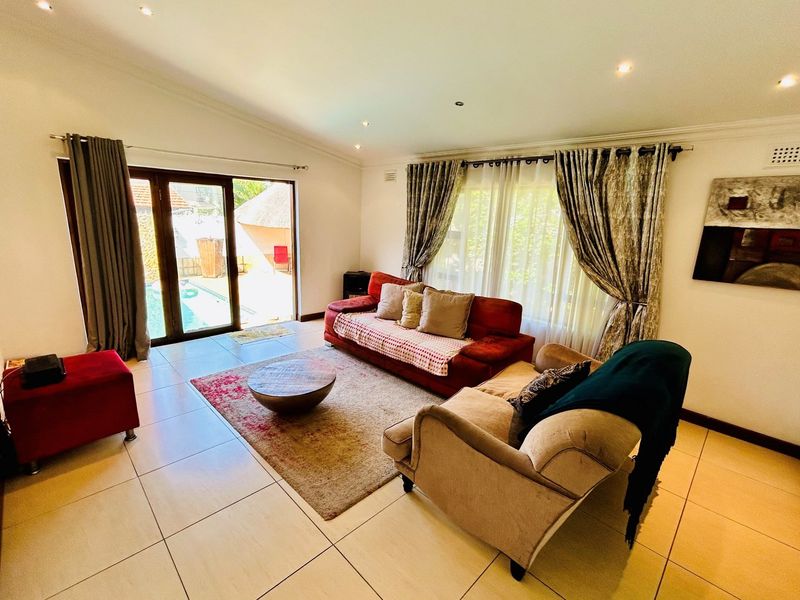 Spacious living room featuring large format floor tiles, recessed downlighting, and sliding glass doors providing direct access to the outdoor pool area.