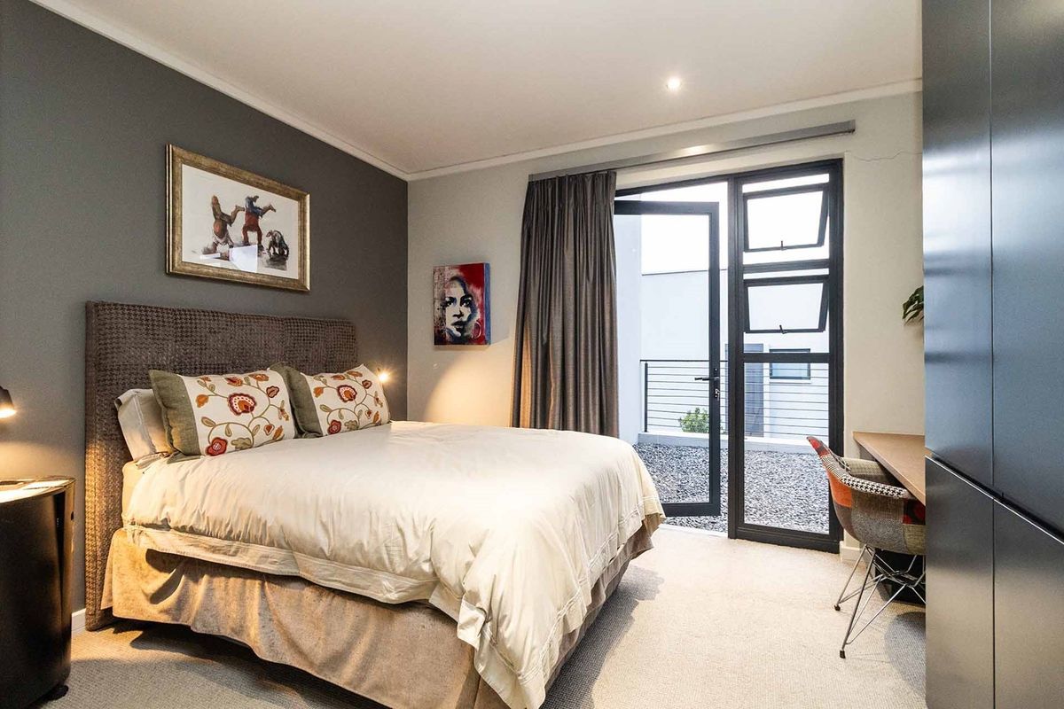 A well-maintained bedroom featuring built-in cupboards, carpeted flooring, and direct access to an outdoor patio area through a glass door.