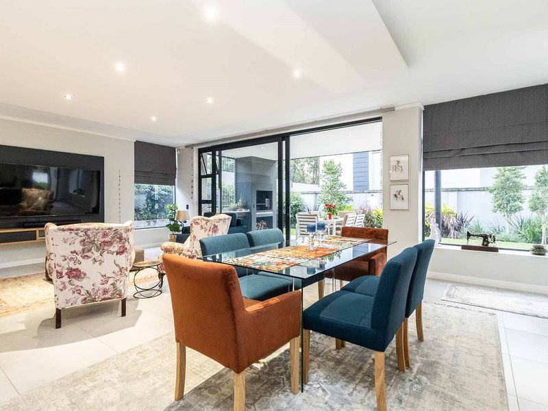 Spacious open-plan living and dining area featuring modern tiled floors, recessed lighting, and large sliding glass doors that open to an outdoor patio.