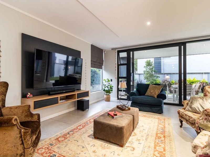 Modern living room featuring large format floor tiles, a sleek built-in media console, and expansive sliding glass doors providing seamless access to the patio.