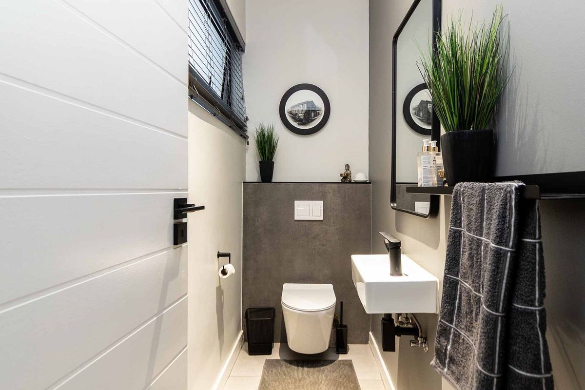 Modern guest cloakroom featuring a wall-mounted toilet, sleek wall-mounted basin, and contemporary dark grey tiled accents.