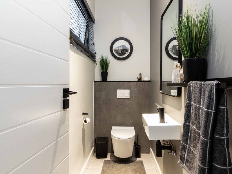 Modern guest cloakroom featuring a wall-mounted toilet, sleek wall-mounted basin, and contemporary dark grey tiled accents.