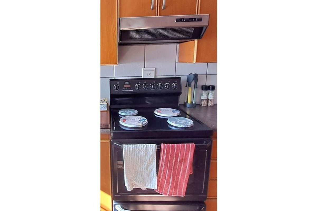 A kitchen area featuring a built-in oven and hob with an overhead extractor fan and tiled splashback.