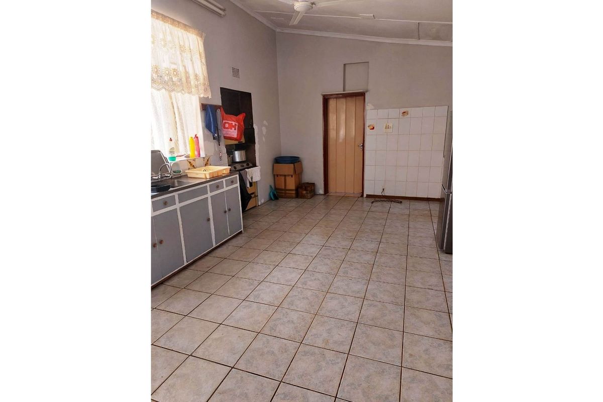 A functional kitchen area featuring tiled flooring, built-in cabinetry, and tiled splashbacks, offering a blank canvas for potential renovation and modernization.