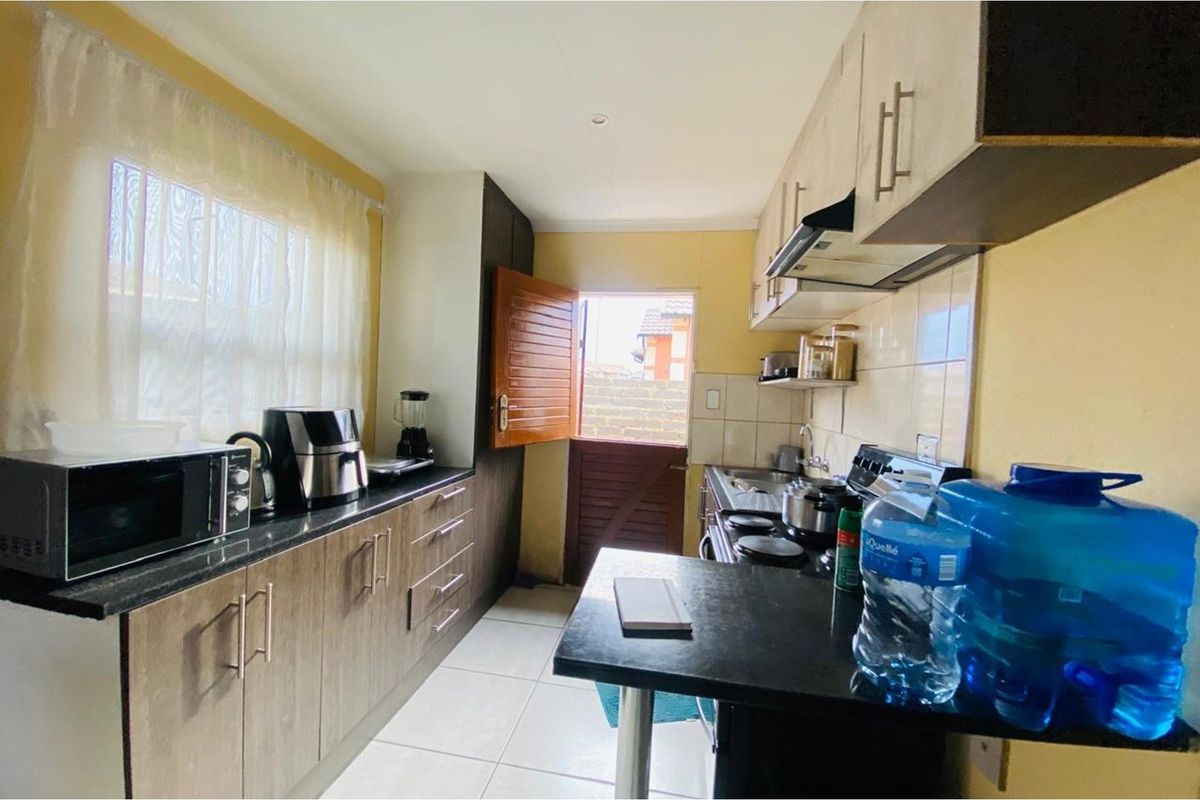 A functional kitchen featuring built-in cabinetry, granite countertops, a hob with extractor fan, and direct access to the exterior via a stable door.