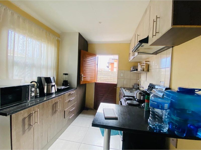 A functional kitchen featuring built-in cabinetry, granite countertops, a hob with extractor fan, and direct access to the exterior via a stable door.