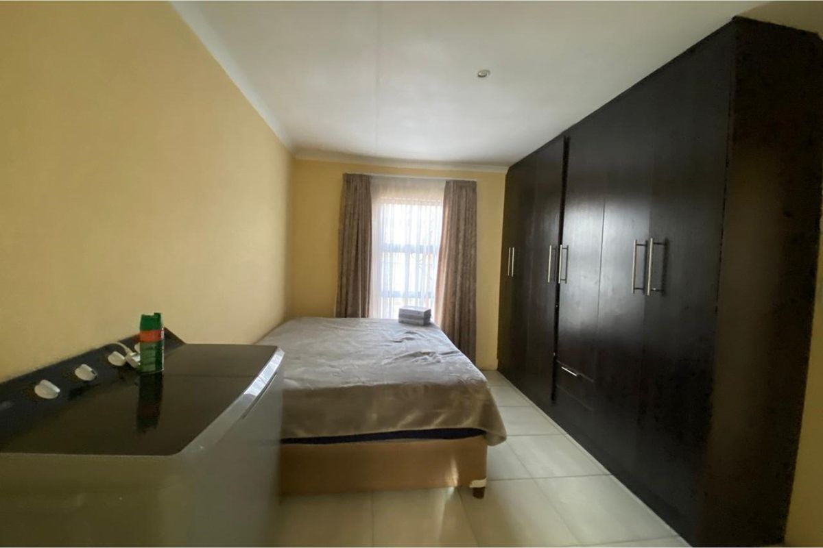 A bedroom featuring tiled flooring and extensive dark wood built-in cupboards, providing ample storage space.