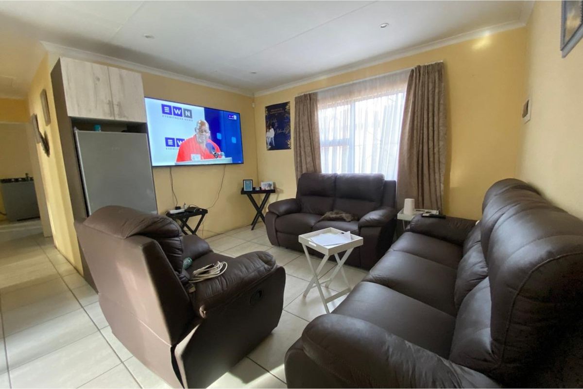 A functional living room featuring tiled flooring, recessed ceiling lighting, and coved cornicing, providing a comfortable and practical space for relaxation.