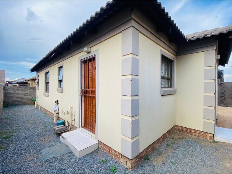 Rear exterior view of the house featuring a security gate, tiled roof, and gravel ground cover.