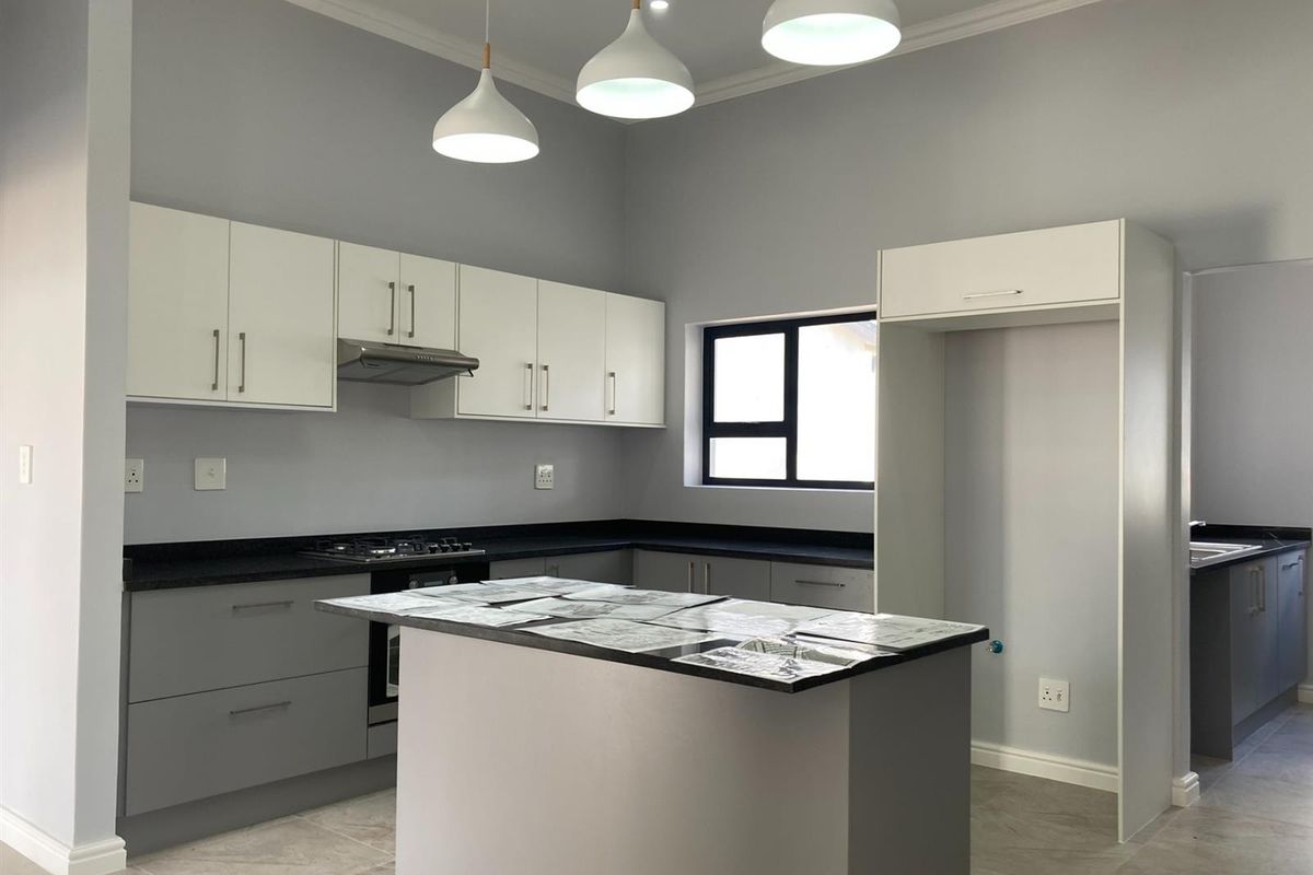 Modern kitchen featuring grey and white cabinetry, stone countertops, a central island, and built-in gas hob with extractor fan.