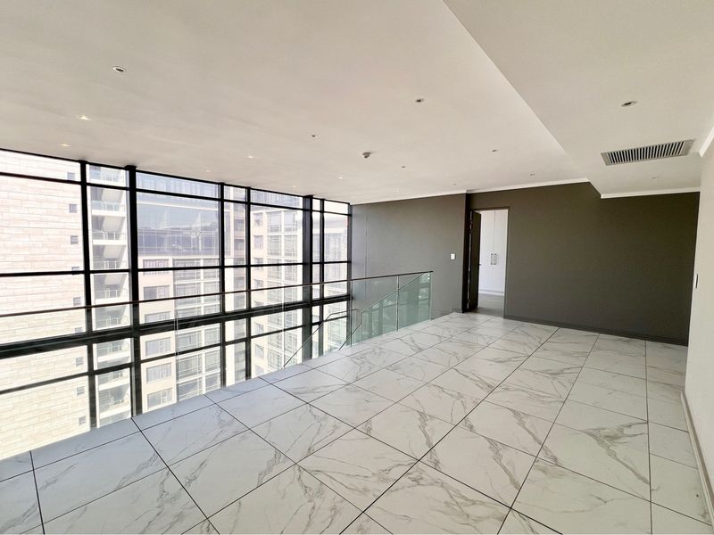 Spacious penthouse living area featuring floor-to-ceiling windows, glass balustrade, and modern marble-look tile flooring with integrated climate control.
