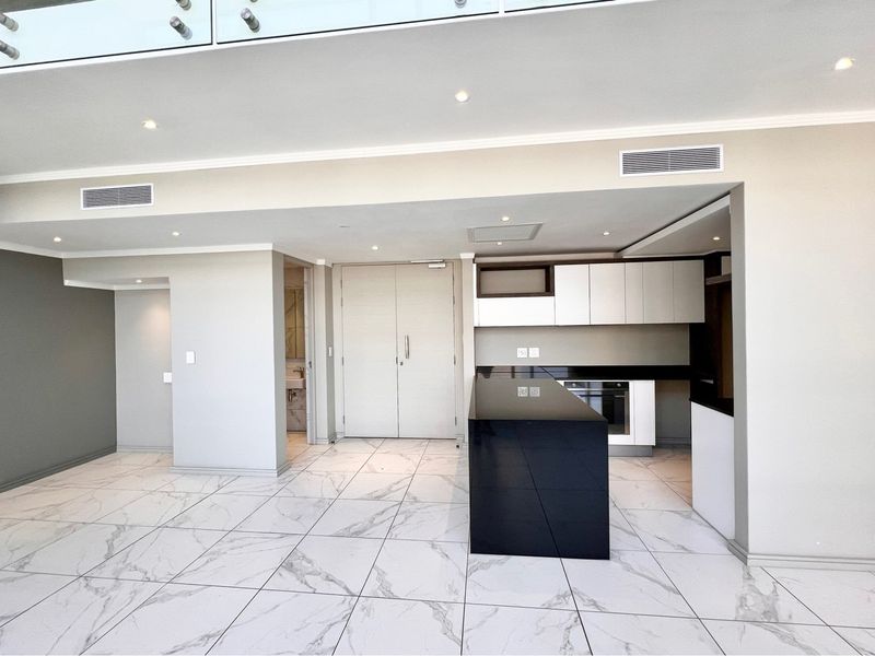 Modern open-plan living area featuring sleek kitchen cabinetry, a central island, marble-look tiled flooring, and contemporary recessed lighting in a penthouse setting.