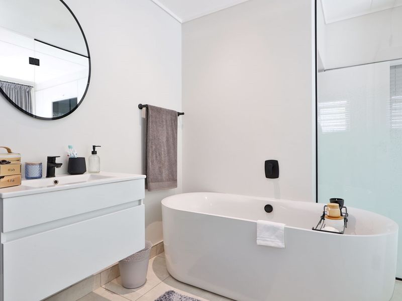 Modern bathroom featuring a sleek freestanding bathtub, wall-mounted fixtures, a contemporary vanity cabinet, and a separate shower enclosure with clean finishes.
