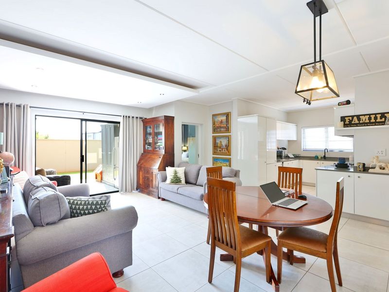 Spacious open-plan living and dining area featuring tiled floors, modern recessed lighting, and a functional kitchen with integrated cabinetry and island.
