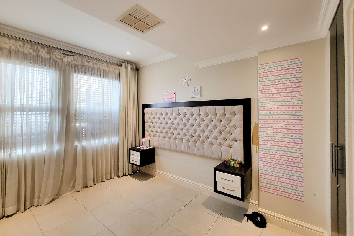 A well-maintained bedroom featuring a built-in tufted headboard with integrated floating bedside tables and tiled flooring.