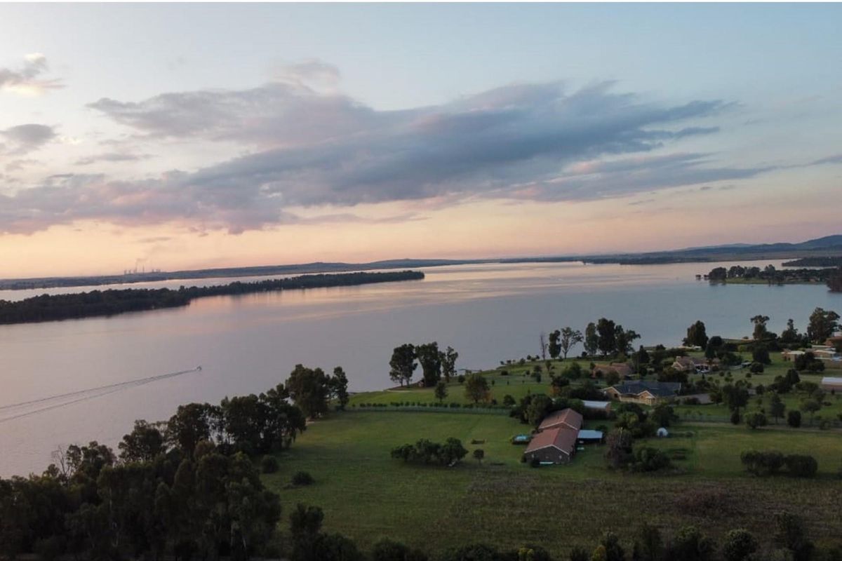 An aerial view of a large residential land parcel featuring expansive waterfront access and established greenery in a peaceful setting.