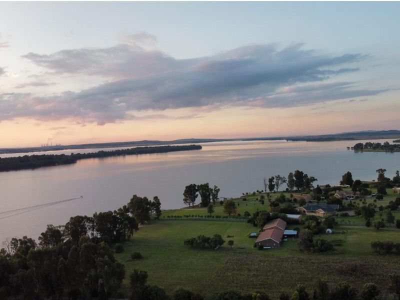 An aerial view of a large residential land parcel featuring expansive waterfront access and established greenery in a peaceful setting.
