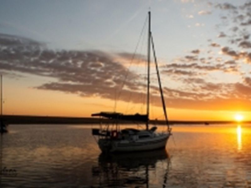 A scenic sunset view over the water featuring sailboats, highlighting the tranquil coastal or lakeside location of the property.