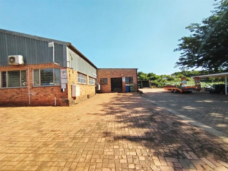 Exterior view of an industrial property featuring brick facade, metal cladding, paved yard area, and secure access points.