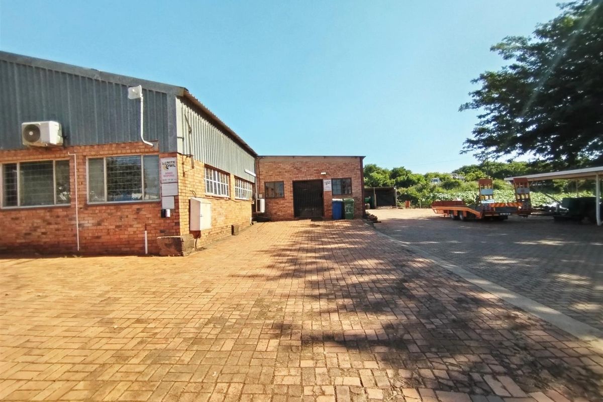 Exterior view of an industrial property featuring brick facade, metal cladding, paved yard area, and secure access points.