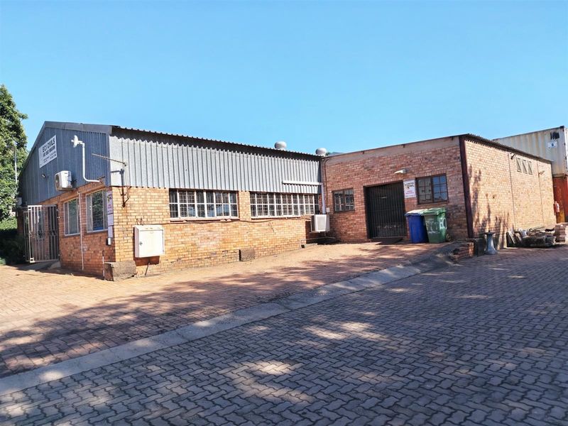 Industrial property featuring a combination of face brick and corrugated metal cladding with paved exterior access and secure gated entrance.