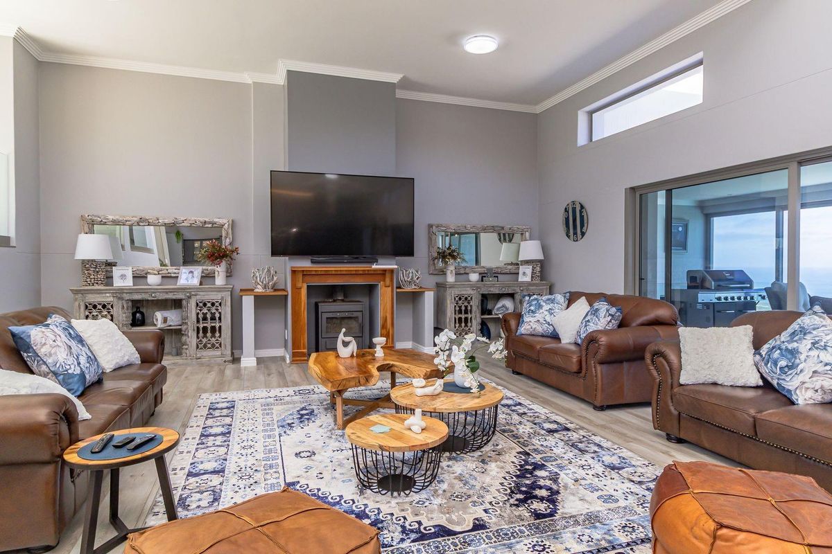 Spacious living room featuring a central fireplace, high ceilings with clerestory windows, and large sliding glass doors leading to an outdoor area.