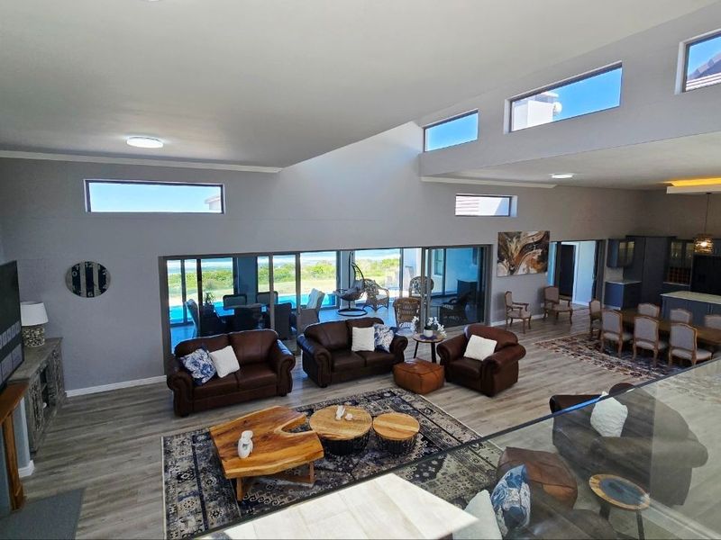 Spacious open-plan living and dining area featuring vaulted ceilings, clerestory windows, and large sliding glass doors that provide seamless access to the outdoor patio.