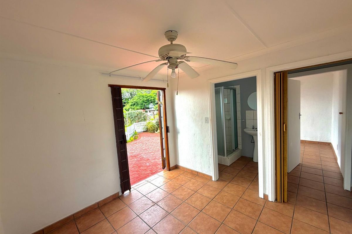 An empty bedroom featuring tiled flooring, a ceiling fan, and direct access to an en-suite bathroom and outdoor patio area.