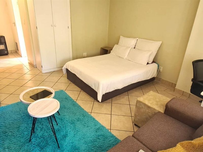 An open-plan studio apartment featuring tiled flooring and a built-in wardrobe, offering a functional living and sleeping space.