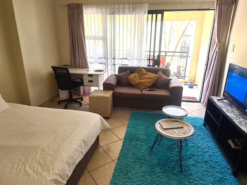 An open-plan studio apartment featuring tiled flooring and direct access to a balcony through sliding glass doors.