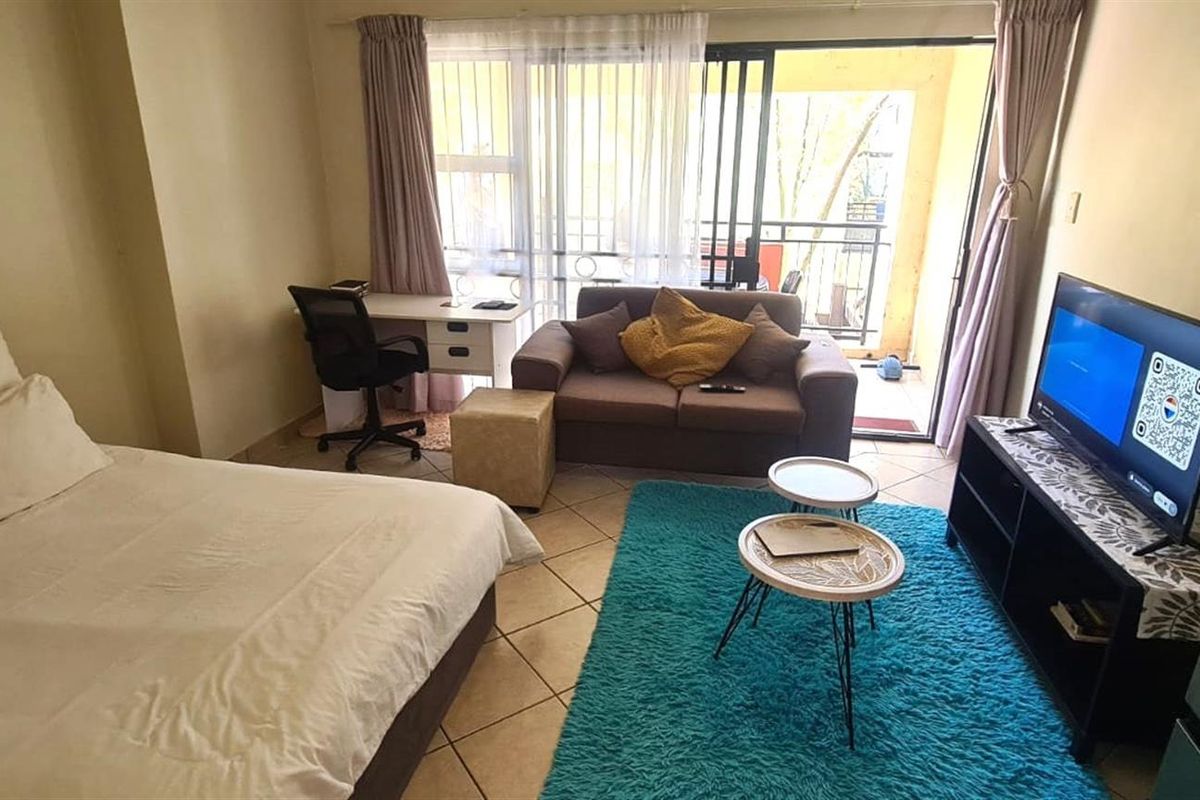 An open-plan studio apartment featuring tiled flooring and direct access to a balcony through sliding glass doors.