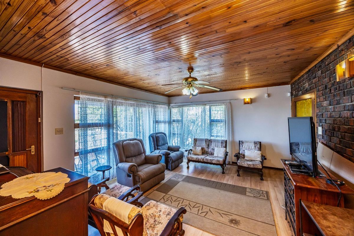 A living room featuring a warm timber-clad ceiling, exposed brick wall, and large windows that provide ample natural light.