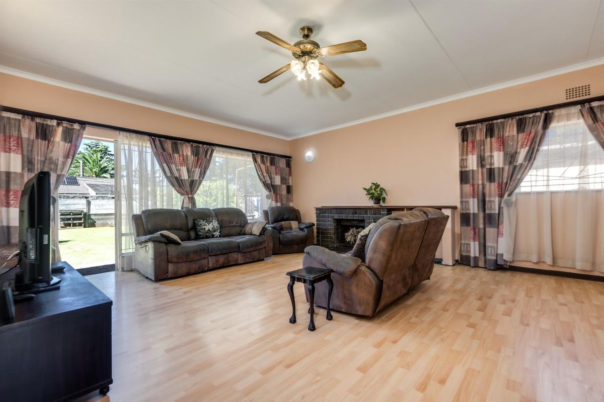 Spacious living room featuring light wood-look flooring, a built-in fireplace, and large sliding glass doors providing direct access to the rear garden.