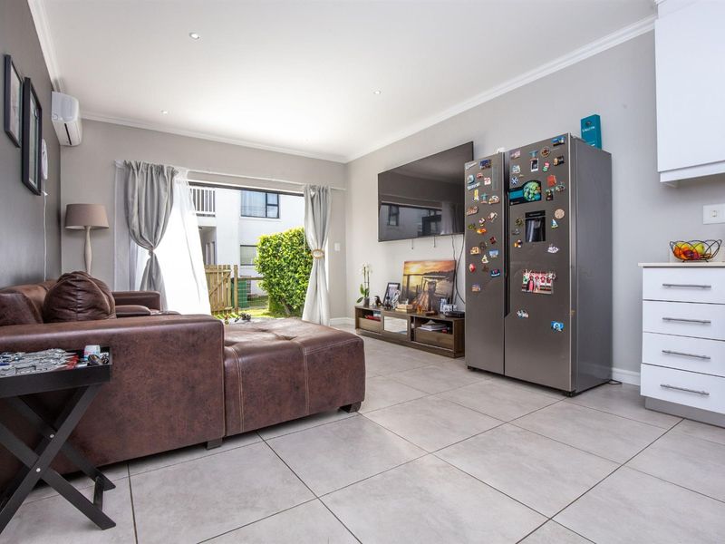 Open-plan living area featuring tiled flooring, recessed lighting, and a modern kitchen layout with direct access to an outdoor patio space.