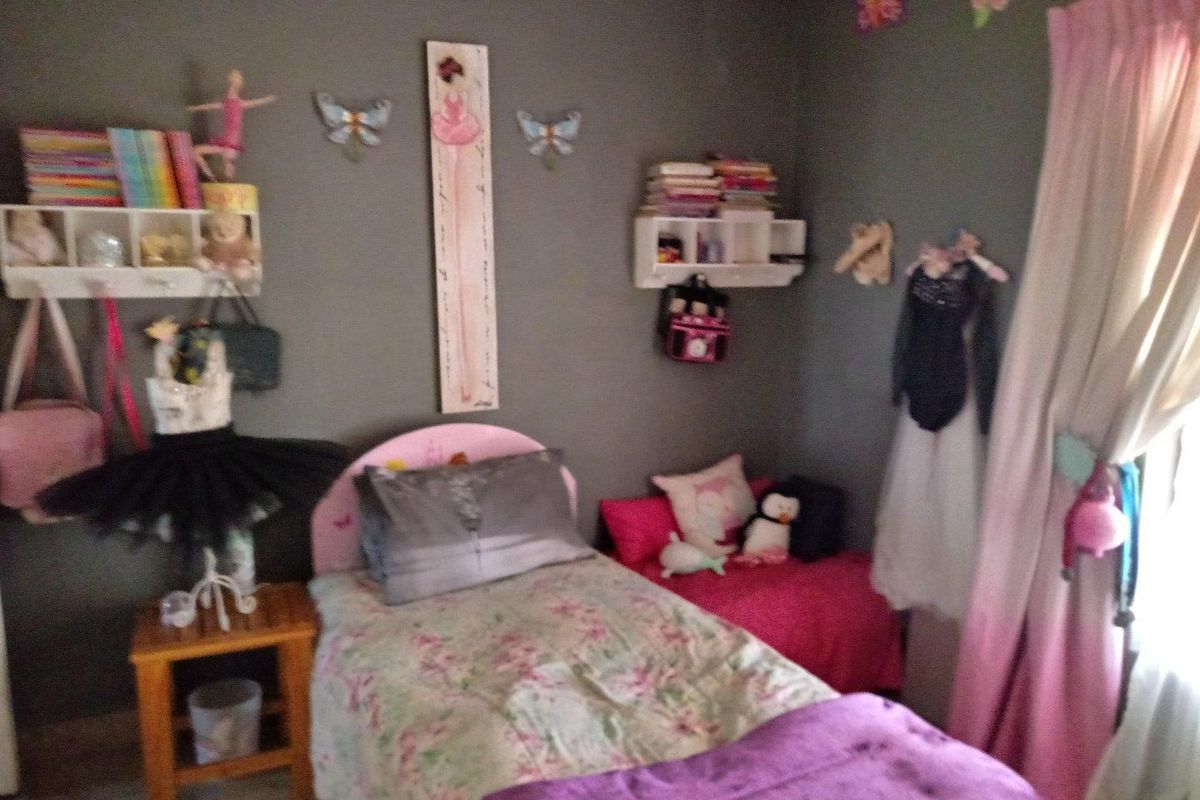 A bedroom featuring grey walls, built-in shelving units, and a window with curtains.