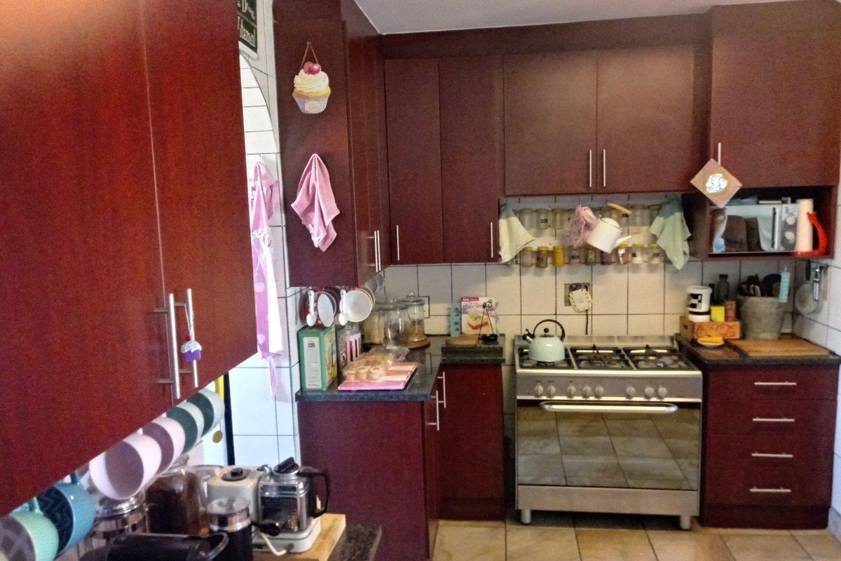 A functional kitchen featuring dark wood-toned cabinetry, tiled flooring, a tiled backsplash, and a built-in gas stove with an oven.