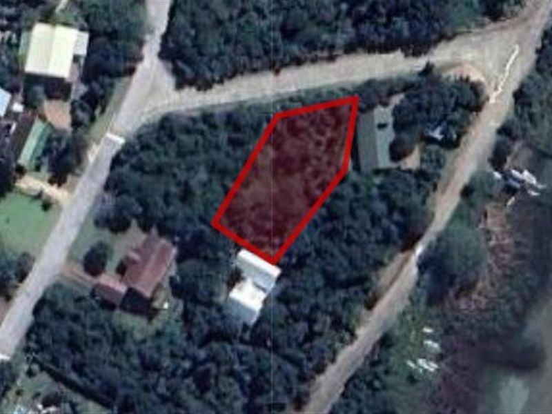 Aerial view of a vacant residential plot highlighted in red, situated in a coastal or semi-rural neighborhood setting.
