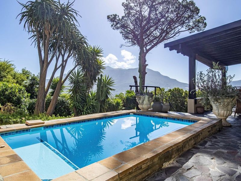 A well-maintained swimming pool area featuring stone paving and a covered patio with mountain views.