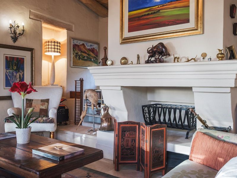 A cozy living room featuring a prominent masonry fireplace, exposed timber ceiling beams, and warm ambient lighting.